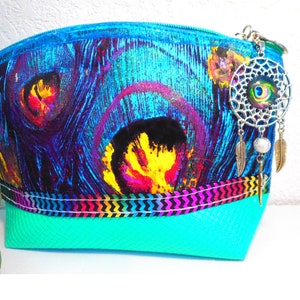 May include: A colourful cosmetic bag with a peacock feather pattern in blues, purples, yellows, and reds. It has a turquoise base and a decorative trim. A dreamcatcher charm hangs from the zipper.