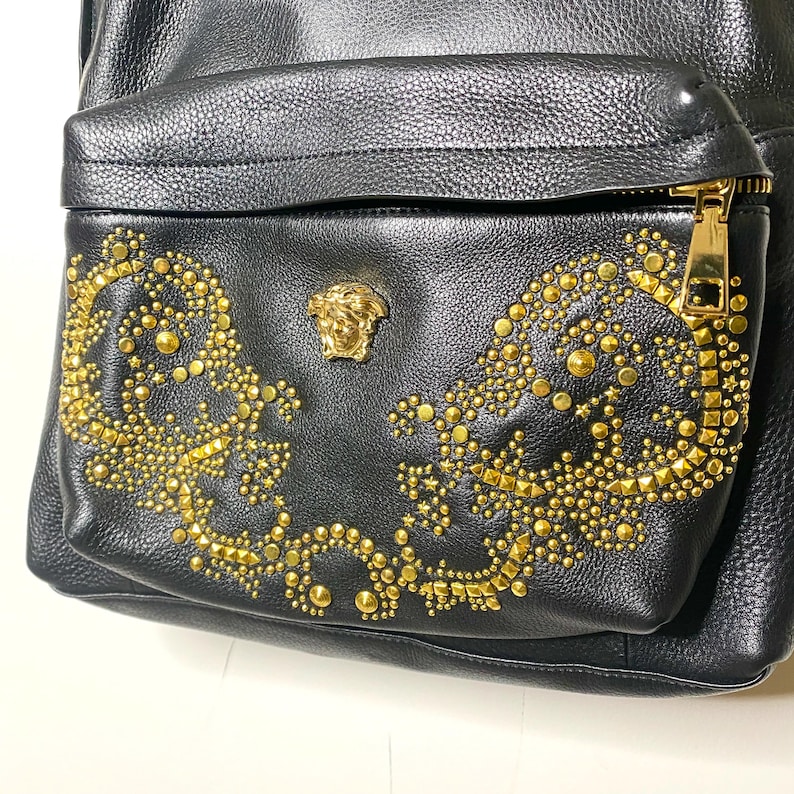 May include: A white ceramic mug with a black handle and the text "But First, Coffee" in a black, handwritten-style font. The mug is on a white surface.