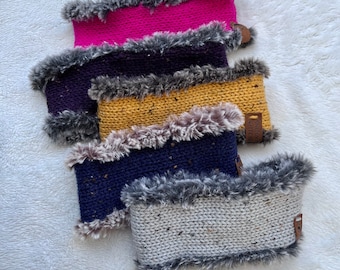 Könnte beinhalten: Vier gestrickte Halstücher mit Kunstfellbesatz. Die Tücher sind in Pink, Lila, Gelb und Grau. Die Tücher haben ein Etikett mit der Aufschrift "Snug Stitch".