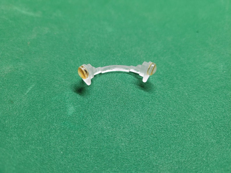 May include: A clear plastic nose bridge with gold-colored accents on each end.