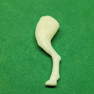 Puede incluir: Un modelo de pierna de caballo de plástico blanco, con una superficie texturizada y una pezuña redondeada.