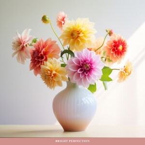 May include: A white ceramic vase with a textured surface holds a bouquet of pink, orange, and yellow dahlias. The flowers are arranged in a loose, natural style.