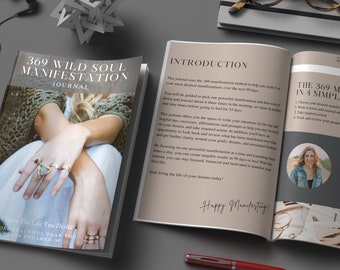 May include: An open journal with the title "369 Wild Soul Manifestation Journal" and the text "Create The Life You Desire More Beautiful Than You Ever Dreamed Of." The journal is open to a page with the introduction and instructions. A red pen and eyeglasses are also visible.