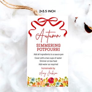 May include: A white rectangular tag with the text "Autumn Simmering Potpourri" in red script. The tag includes instructions and is 2 x 3.5 inches. A red bow design is at the top, and a floral border is at the bottom.