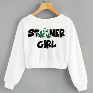 May include: White cropped sweatshirt with long sleeves and the text "STONER GIRL" in black with green marijuana leaf graphics.