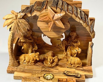 May include: A carved wooden nativity scene with figures of Mary, Joseph, and baby Jesus in a manger. The scene is set within a rustic wooden structure with a star and the word "Bethlehem".