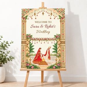 May include: A rectangular wedding welcome sign on a wooden easel featuring an illustration of a couple in traditional attire standing by a fire. The sign has a cream background with ornate floral pillars and the text Welcome to Sara & Rohit's Wedding.