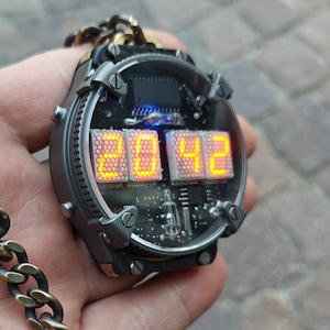May include: A steampunk-style digital watch pendant displaying the time 20:42 in bright orange digits. The watch features a circuit board design, a metal frame, and a chain.