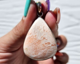 May include: A teardrop-shaped pendant with a silver setting and a pink and white coral stone.