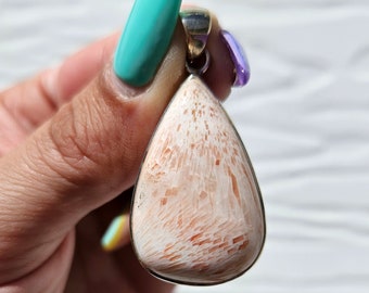 May include: A teardrop-shaped pendant with a white and orange coral stone set in silver.