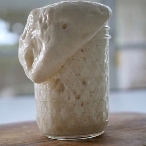 May include: A glass jar with a white, foamy substance rising above the rim. The jar has a textured, diamond-shaped pattern.