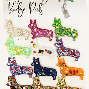 May include: A collection of twelve Corgi-shaped badge reels featuring various holiday and seasonal themes, including glitter, stars, leaves, and school supplies. The text "Corgi Holiday Badge Reels" is displayed at the top of the image.