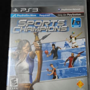 May include: A PlayStation 3 game case for Sports Champions. The case is white with a blue and red design. The game features a variety of sports, including archery, table tennis, and volleyball. The game requires a PlayStation Move controller.