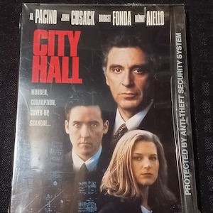 May include: DVD cover for the movie City Hall starring Al Pacino, John Cusack, Bridget Fonda, and Danny Aiello. The cover features a close-up of Al Pacino looking directly at the viewer. The title of the movie is in large, bold letters.