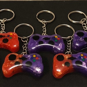 May include: Eight colorful game controller keychains, half red and half purple with black buttons, attached to silver key rings.