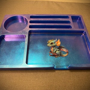 May include: A blue and purple resin tray with compartments for dice and other gaming accessories. The tray features a small, colorful dragon illustration.