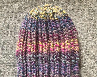May include: A colorful knitted beanie hat with a striped pattern in shades of pink, purple, blue, and yellow.