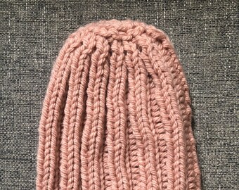 May include: A pink knitted beanie hat with a ribbed texture.