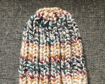 May include: A white knit beanie with a colorful yarn pattern. The beanie has a slouchy fit and is made with a chunky yarn.