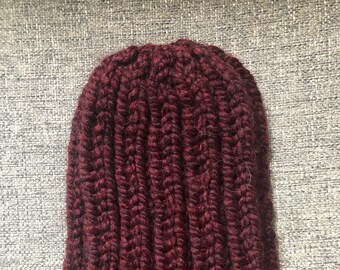 May include: A burgundy knitted beanie hat with a ribbed texture.