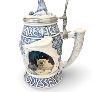 以下が含まれることがあります： 青と白のデザインのセラミック製ビアマグ。「ARCTIC」と「ODYSSEY」の文字が特徴。前面にはホッキョクグマが描かれています。蓋にはセイウチの置物が付いています。