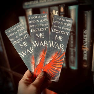 May include: Three rectangular bookmarks with a dark background and the text "I WOULD HAVE LIVED IN PEACE, BUT MY ENEMIES BROUGHT ME WAR." Each bookmark features a red wing design.