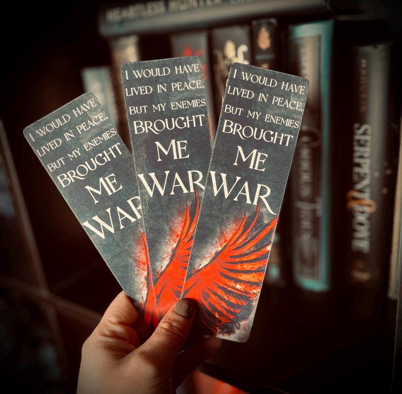 May include: Three rectangular bookmarks with a dark background and the text "I WOULD HAVE LIVED IN PEACE, BUT MY ENEMIES BROUGHT ME WAR." Each bookmark features a red wing design.