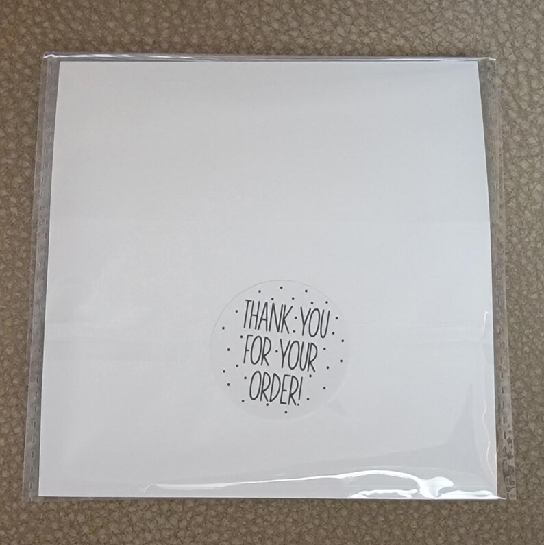 Puede incluir: Tarjeta blanca con una pegatina en blanco y negro que dice "&iexcl;Gracias por tu pedido!"