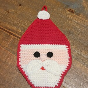May include: A crocheted Santa Claus pot holder with a red hat, white beard, and black eyes.