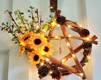 May include: A cinnamon stick star with fairy lights wrapped around it. The star is decorated with dried flowers and pinecones.