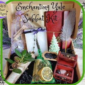 May include: An open box filled with Yule Sabbat Kit items. The kit includes a red journal, a white Christmas tree candle, a feather, a small wooden chest with crystals, a bundle of dried lemon slices, and a Yule Garland Kit sign.
