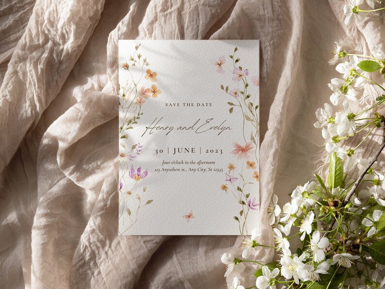 Puede incluir: Tarjeta de guardar la fecha con ilustraciones florales de acuarela. La tarjeta dice "Save the Date, Henry y Evelyn, 30 de junio de 2023, cuatro en punto de la tarde, 123 Anywhere st, Any City, St 12345."