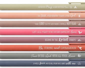 May include: A set of eight retractable ballpoint pens in various muted colors, each featuring a unique white printed religious quote and a small icon. The pens are arranged horizontally, displaying phrases like Always Pray, Be Still, and Trust in the Lord.
