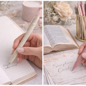 May include: Two retractable ballpoint pens in beige and dusty rose, each featuring a clip and white printed text. The beige pen reads Pray without ceasing, while the dusty rose pen displays the text Be still and know with small heart icons.