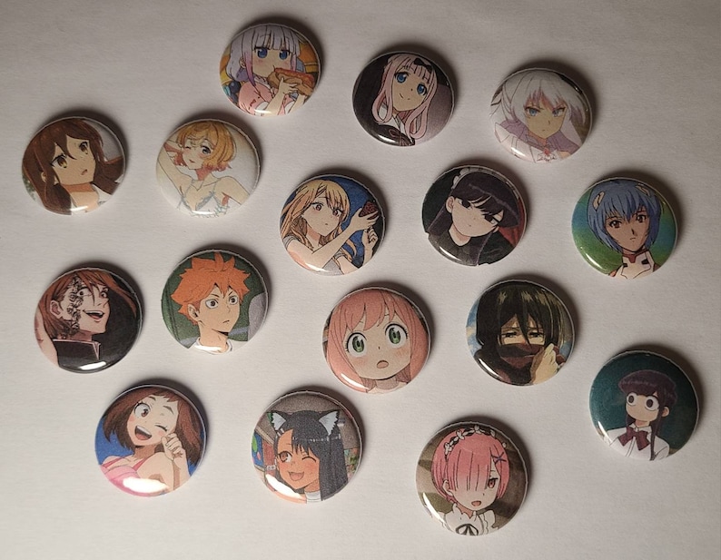 May include: A collection of 15 round anime character buttons. The buttons feature various characters from popular anime series, including a girl with pink hair, a girl with blue hair, a girl with brown hair, and a boy with orange hair. The buttons are all different sizes and shapes, and they are all made of metal.