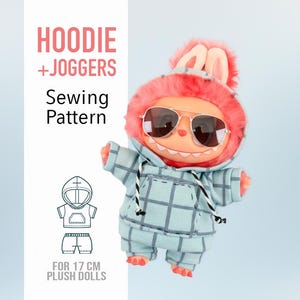 May include: A plush doll wearing a blue plaid hoodie and joggers, with sunglasses and a pink furry hood with bunny ears. The image includes text that reads "HOODIE + JOGGERS Sewing Pattern" and "FOR 17 CM PLUSH DOLLS".