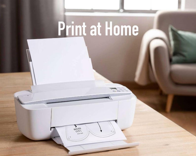 May include: A white printer with a sheet of paper in the tray. The paper has a design for a face mask with the words "Mouth Cut 1" printed on it. The text "Print at Home" is visible above the printer.