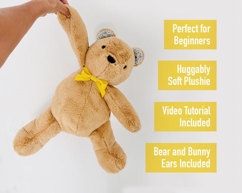 May include: A brown teddy bear with a yellow bow tie and floral ears. The bear is being held up by a hand. The text "Perfect for Beginners", "Huggably Soft Plushie", "Video Tutorial Included", and "Bear and Bunny Ears Included" is written in yellow boxes.