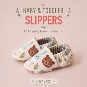 May include: A pair of baby and toddler slippers featuring a cream-coloured fabric with a repeating pattern of brown bears, blue rabbits, and green leaves. The slippers have an elasticated opening and a striped interior lining. Text reads BABY & TODDLER SLIPPERS PDF Sewing Pattern + Tutorial 0-6 YEARS.