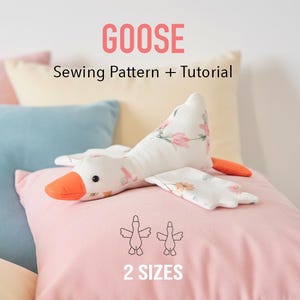 Puede incluir: Un juguete de ganso de peluche con cuerpo blanco, pico naranja y detalles florales en las alas descansa sobre una almohada rosa. La imagen incluye el texto "GOOSE Sewing Pattern + Tutorial" y "2 SIZES". El fondo presenta almohadas pastel.