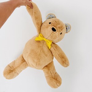 May include: A brown plush teddy bear with yellow ribbon bow and floral fabric ears.