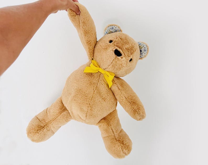 May include: A brown plush teddy bear with yellow ribbon bow and floral fabric ears.