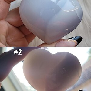 May include: A heart-shaped, polished stone in shades of pale blue and white. The stone is smooth and reflective, with subtle variations in color. The image includes the text "#7".