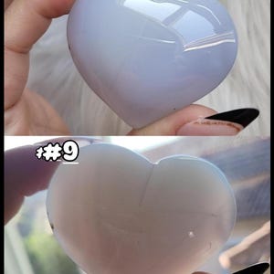 May include: Two heart-shaped stones are shown, one light blue and the other off-white. The stones are smooth and polished, with a glossy finish. The top stone is held by a hand with a light pink nail. The bottom stone has the number "#9" in the upper left corner.