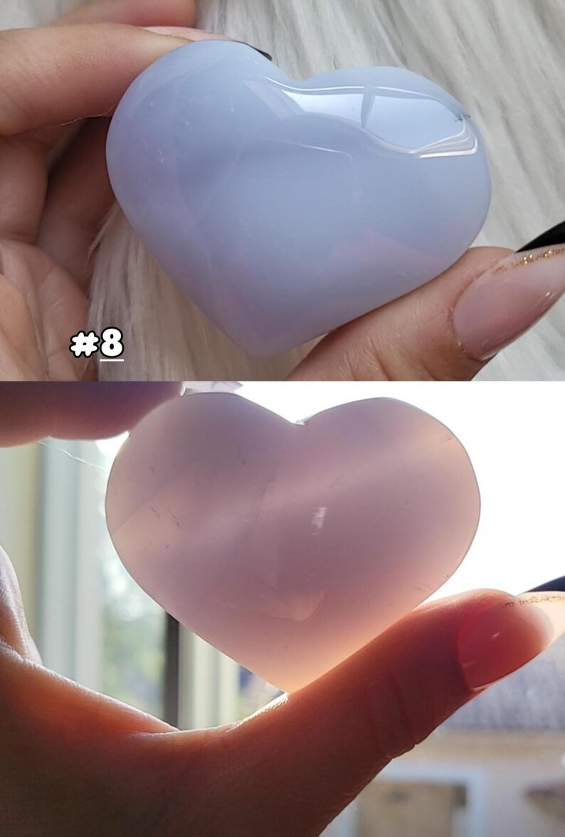 May include: Two heart-shaped stones, one light blue and the other pink, are held in a hand. The blue stone has a glossy finish, while the pink stone appears translucent. The number "#8" is visible in the image.