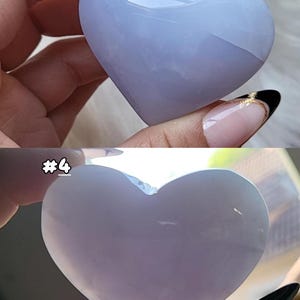 May include: Two heart-shaped stones, one light blue and the other a pale lavender, are held in hands. The light blue stone is more translucent. The stones are smooth and polished, with a glossy finish. The image includes the text "#4".