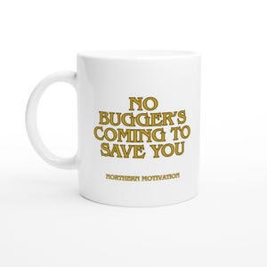 Può includere: Una tazza in ceramica bianca con un manico sul lato sinistro. La tazza presenta un testo color oro che recita NO BUGGER'S COMING TO SAVE YOU in grandi lettere, con il testo più piccolo NORTHERN MOTIVATION stampato direttamente sotto la frase.