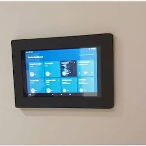 May include: A black framed tablet mounted on a white wall. The screen displays a blue interface with the text "Device Dashboard" and several icons.