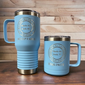 May include: Two blue stainless steel tumblers with gold lettering. The larger tumbler has the text "K's Last Home Game Heels 94 dook 81 3-5-2022 ACCEPTABLE". The smaller tumbler has the text "Heels End K's Last Dance Heels 81 dook 77 04-02-2022 EXQUISITE".