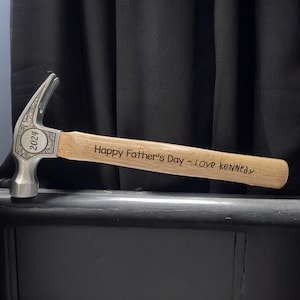 Może przedstawiać: Srebrny młotek z drewnianym trzonkiem. Trzonek jest grawerowany tekstem "Happy Father's Day - Love kennedy" i rokiem "2024".